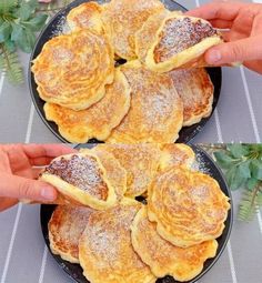 two plates with pancakes on them being held by hands