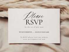 a white wedding card with black lettering on it sitting on a fur - covered surface