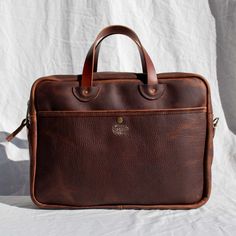 What you'll love about it: Fit for the office and important meetings, but without the stuffiness. This handcrafted briefcase holds a laptop, paperwork, a notebook or two, and more. This rugged and sturdy leather comes in unique coyote color. Sits comfortably on a hip as you stride into work. The detachable strap adjusts to throw over your shoulder or as a crossbody. Use the inner and outer pockets for the small stuff, like pens, your phone, and keys. The inside button-down laptop pocket with pen Leather-lined Briefcase For Office With Shoulder Strap, Luxury Vegetable-tanned Leather Briefcase For Travel, Rugged Leather-backed Briefcase For Business, Vintage Brown Leather-lined Rectangular Briefcase, Rectangular Briefcase With Zipper Closure For On-the-go, Copper Hardware, Throw Over, Laptop Pocket, The Office