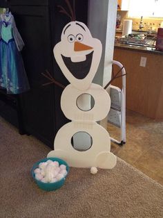 a cardboard snowman made to look like it is standing next to a bowl of marshmallows