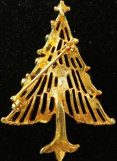 a gold christmas tree brooch on a black background