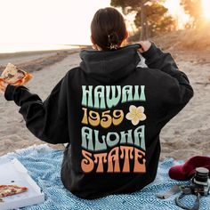 Hawaii Aloha State Retro Unisex Hoodie Please size up 1 to 3 sizes for an oversized look! This unisex heavy blend hooded sweatshirt is relaxation itself. Made with a thick blend of cotton and polyester, it feels plush, soft  and warm, a perfect choice for any cold day. In the front, the spacious kangaroo pocket adds daily practicality while the hood's drawstring is the same color as the base sweater for extra style points. .: 50% cotton, 50% polyester (fiber content may vary for different colors) .: Medium-heavy fabric (8.0 oz/yd² (271 g/m .: Classic fit .: Tear-away label .: Runs true to size Thank you for supporting a small business! Casual Vacation Hoodie With Letter Print, Casual Hoodie With Letter Print For Vacation, Casual Letter Print Hoodie For Vacation, Vacation Hoodie Sweatshirt With Letter Print, Winter Vacation Hoodie With Letter Print, Oversized Graphic Print Hoodie For Vacation, Oversized Letter Print Hoodie For Vacation, Oversized Hoodie With Letter Print For Vacation, Casual Graphic Print Hoodie For Vacation