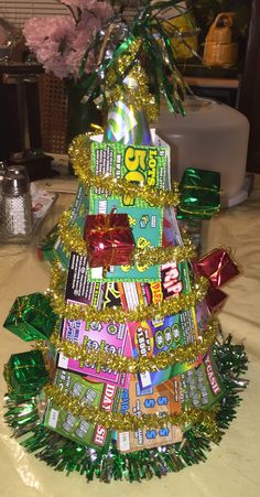 a christmas tree made out of candy bar wrappers and tinsel wrapped around it