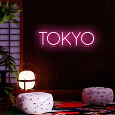 the neon tokyo sign is lit up in front of a room with two stools