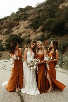 four bridesmaids pose for a photo in front of a mountain side with their bouquets