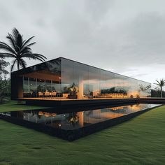 a large glass building sitting on top of a lush green field next to a lake