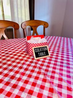 a table with a red and white checkered table cloth on it that says isolation table