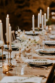 a long table is set with white flowers and place settings for an elegant dinner party