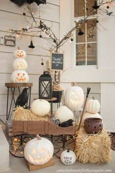 pumpkins and hay bales in front of a house with halloween decorations on the porch