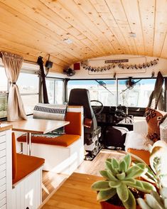 an interior view of a recreational vehicle with wood paneling and white walls, windows, and wooden flooring