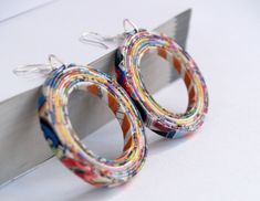 two pairs of multicolored paper hoop earrings sitting on top of a piece of metal