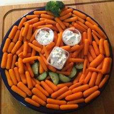 a plate with carrots and cucumbers arranged in the shape of a face