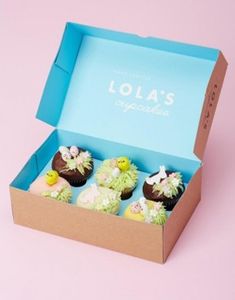 four cupcakes in a blue box on a pink background