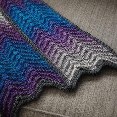 two knitted scarves sitting on top of a couch