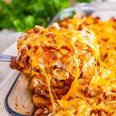 a casserole dish with meat and cheese being lifted from the casserole