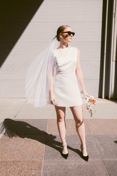 a woman in a white dress and veil walking down the street