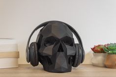 a skull wearing headphones sitting on top of a wooden table next to books and a potted plant