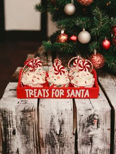 some cupcakes are on a red tray near a christmas tree