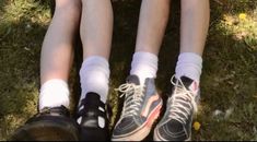 two people sitting on the grass with their feet up wearing tennis socks and running shoes