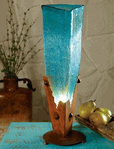 a tall blue vase sitting on top of a table next to some apples and flowers