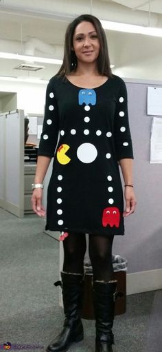 a woman standing in an office wearing black boots and a dress with pacman on it