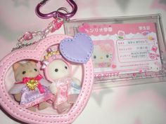 a pink heart shaped keychain with two teddy bears in it and a card holder