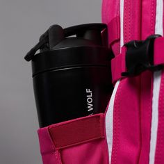 a pink and white backpack with a black coffee cup in it's back pocket