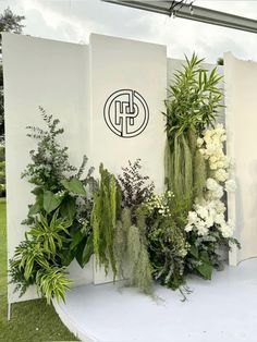 an arrangement of flowers and greenery on display in front of a sign for the company