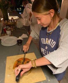 a woman cutting up food on top of a wooden cutting board