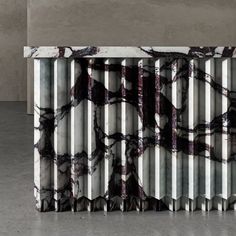 a marble table with metal bars on it and an abstract design in the middle, against a concrete wall