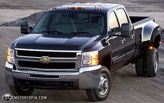 a black pickup truck driving down a dirt road