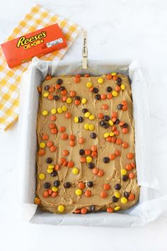 a cake in a pan with candy on top and reese's crackers next to it