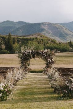 an outdoor ceremony setup with flowers and greenery in the foreground, mountains in the background