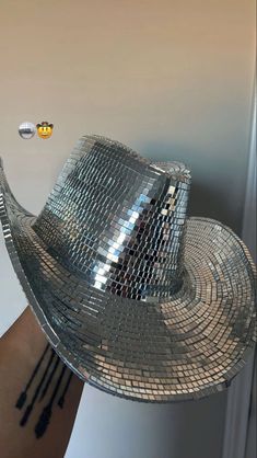 a shiny silver hat hanging from the side of a wall