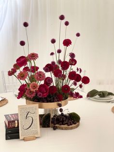 a table topped with flowers and books on top of a white table cloth covered table