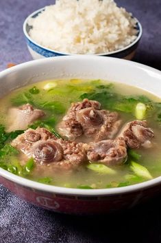 a bowl of soup with meat and broccoli in it next to another bowl of rice