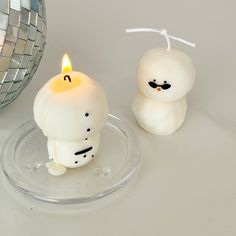 two white candles sitting on top of a glass plate