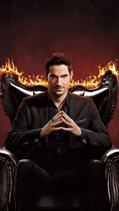 a man sitting in a chair with his hands folded over his chest and fire behind him