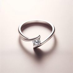 a white gold ring with a single diamond on the top and an invisible band around it