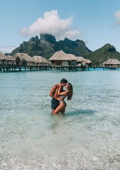 a man and woman in the ocean kissing