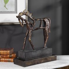 a horse statue sitting on top of a table next to books and a framed picture