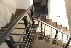 an overhead view of a stair case with tile floors and metal railings, looking down at the door