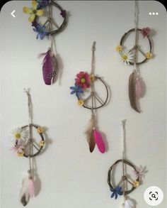 a group of dream catchers with flowers and feathers hanging from the wall next to each other