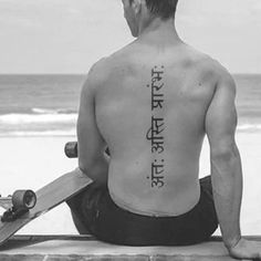 a man sitting on top of a beach next to the ocean holding a skateboard