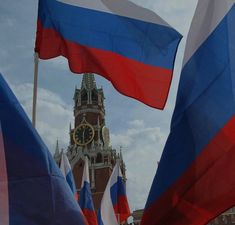 flags blowing in the wind with a clock tower in the background