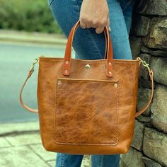 The Claremont Crossbody Tote in Light Umber: Classic, Elegant, and Handcrafted Introducing The Claremont Crossbody Tote—a timeless piece of craftsmanship that combines elegance, functionality, and superior quality. Made from the finest vegetable-tanned full-grain leather, this tote exudes class with its soft, pebbled texture and meticulous attention to detail. The Claremont is a versatile bag, perfect for any occasion, whether you’re carrying it by the hand with the sturdy bridle leather handle or wearing it crossbody with the adjustable and removable strap. Why You’ll Love The Claremont Crossbody Tote: Premium Vegetable-Tanned Leather: Crafted from high-quality, full-grain veg-tanned leather, this tote offers unmatched durability and a luxurious, soft feel. The leather is sourced from som Full Grain Leather Bag, Leather Tote Purse, Elegant Bags, Leather Bag Women, Genuine Leather Bags, Leather Messenger Bag, Classic Elegant, Carry All Bag, Leather Wallet Mens