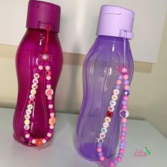 two plastic bottles with beads on them sitting next to each other