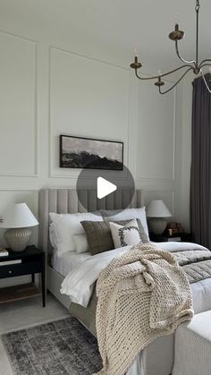 a bed room with a neatly made bed and a chandelier hanging from the ceiling