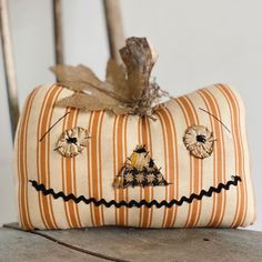 an orange and white striped pillow sitting on top of a wooden chair