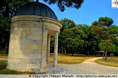 a stone structure with a domed top in the middle of a park